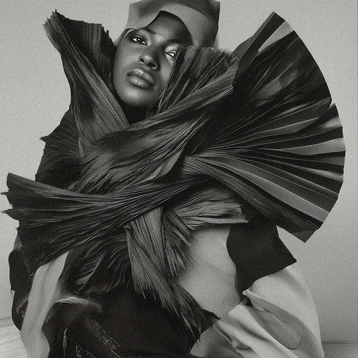 Black-and-white portrait of a woman framed by sculptural pleated fabric